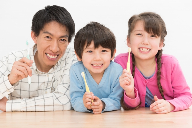 歯ブラシを持つ父親と子供たち